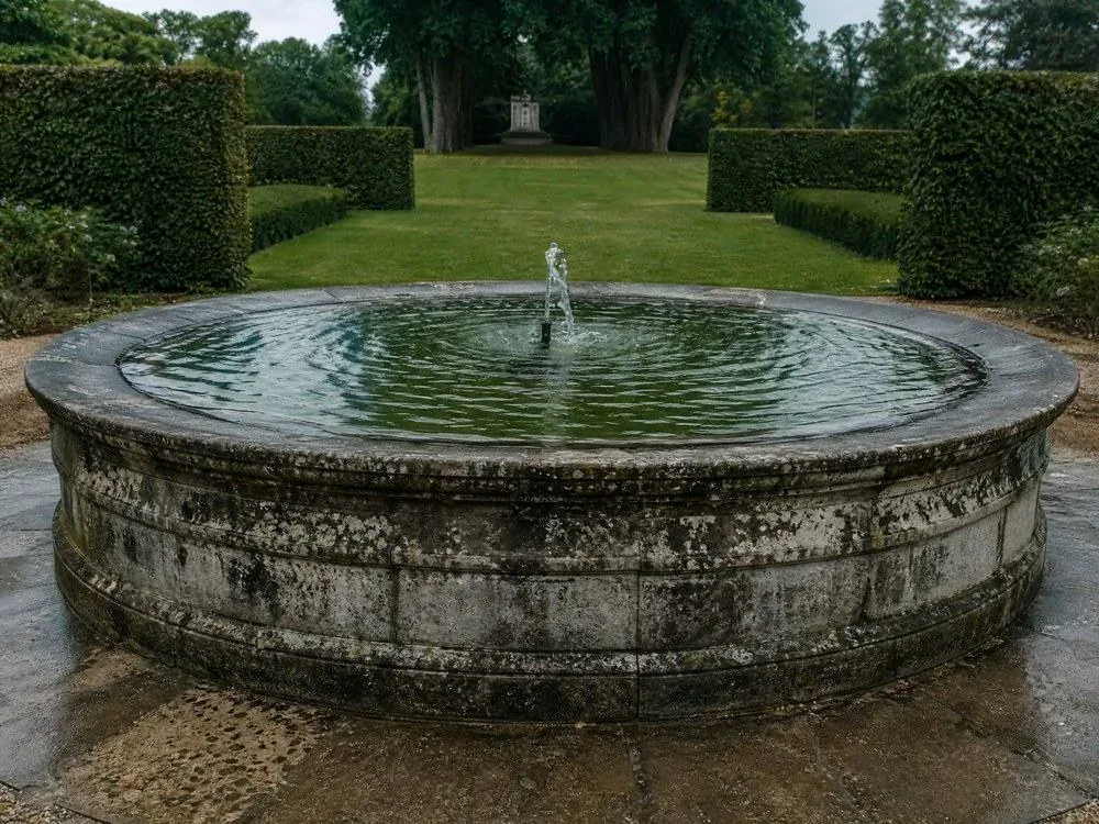 Una fuente de piedra en un jardín formal